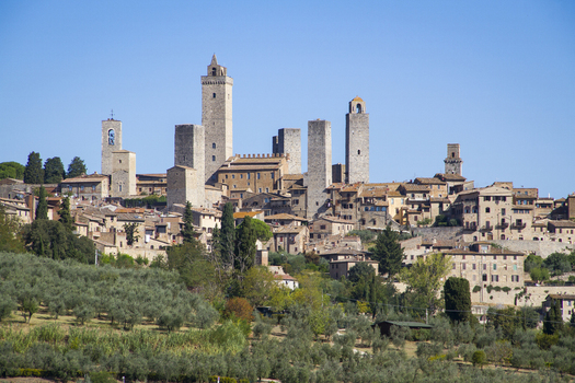 View of medieval towers rise above the terracotta roofs a timeless skyline under a clear blue sky in San Gimignano Tuscany Italy. View of medieval towers rise above the terracotta roofs a timeless skyline under a clear blue sky in San Gimignano Tuscany Italy.