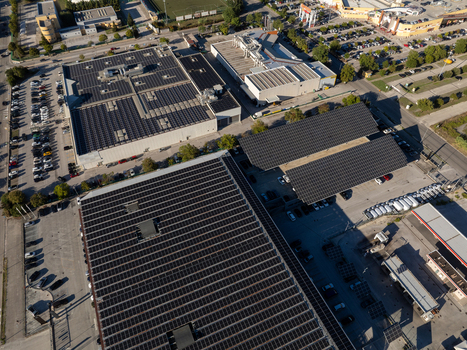 Aerial view of industrial buildings featuring extensive rooftop solar photovoltaic arrays surrounded by parking lots and urban infrastructure in Ancona Marche Italy. Aerial view of industrial buildings featuring extensive rooftop solar photovoltaic arrays surrounded by parking lots and urban infrastructure in Ancona Marche Italy.