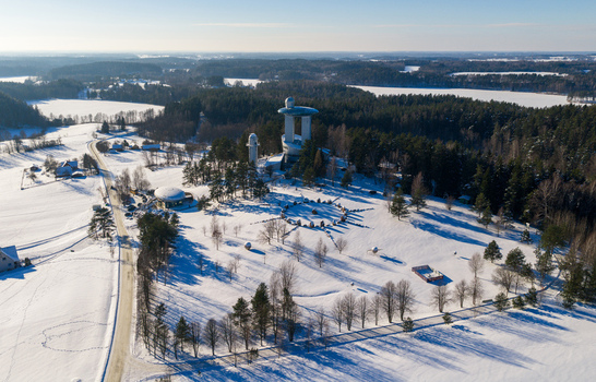 Aerial view of the Lithuanian Museum of Ethnocosmology surrounded by snow covered forests and fields under a clear winter sky in Kulionys Utenos apskritis Lithuania.