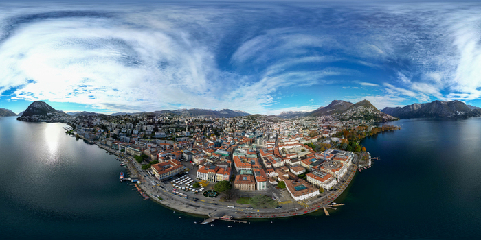Aerial view of the city of Lugano and the surrounding mountains along the shores of Lake Lugano under a blue sky Lugano Ticino Switzerland.