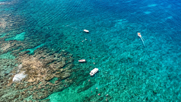 Aerial view of tourists snorkelling over a tropical coral reef with small leisure boats in the turquoise ocean waters Flic en Flac Riviere Noire District Mauritius. Aerial view of tourists snorkelling over a tropical coral reef with small leisure boats in the turquoise ocean waters Flic en Flac Riviere Noire District Mauritius.