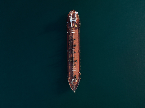 Aerial view of a large industrial tanker ship with a red deck and complex piping navigating through the deep blue sea Augusta Sicily Italy. Aerial view of a large industrial tanker ship with a red deck and complex piping navigating through the deep blue sea Augusta Sicily Italy.