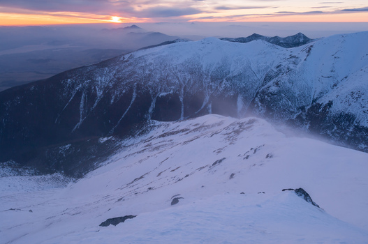 View of Baranec peak in the Western Tatras during a strong winter wind at sunset with snow covered slopes and dramatic light in Jamnik Zilina Region Slovakia. View of Baranec peak in the Western Tatras during a strong winter wind at sunset with snow covered slopes and dramatic light in Jamnik Zilina Region Slovakia.