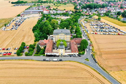 Aerial view of Schloss Jagersburg featuring its baroque architecture and courtyard surrounded by lush green trees and golden fields in Eggolsheim Bayern Germany. Aerial view of Schloss Jagersburg featuring its baroque architecture and courtyard surrounded by lush green trees and golden fields in Eggolsheim Bayern Germany.
