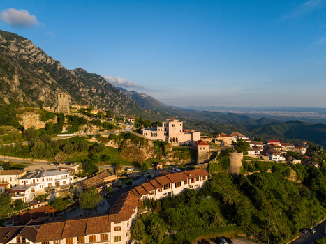 Aerial view of the historic Kruje Castle with its stone fortifications and red tiled rooftops nestled against the rugged mountains under a clear blue sky in Kruje Durres County Albania.