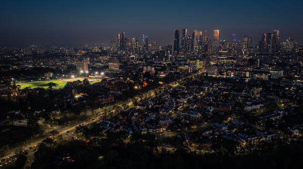 Aerial view of the illuminated Melbourne skyline at night featuring the residential streets and a bright sports field in Parkville Victoria Australia. Aerial view of the illuminated Melbourne skyline at night featuring the residential streets and a bright sports field in Parkville Victoria Australia.