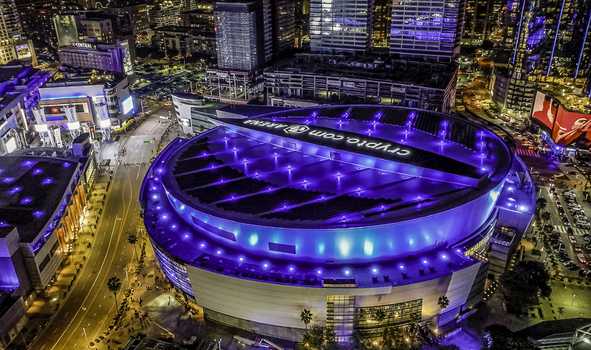 Los Angeles United States 18 February 2023 Aerial view of the Crypto.com Arena glowing with vibrant blue lights contrasting against the city s illuminated skyline.
