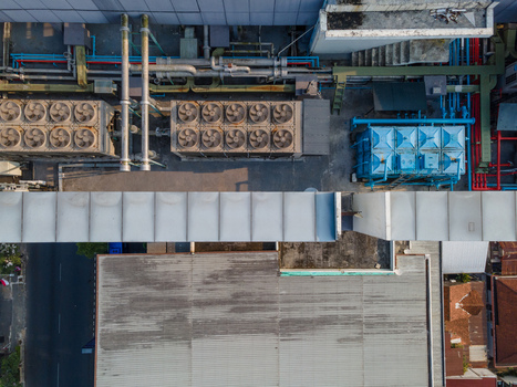 Aerial view of industrial rooftop featuring large HVAC cooling units complex piping systems and ventilation ducts in Purwokerto Central Java Indonesia. Aerial view of industrial rooftop featuring large HVAC cooling units complex piping systems and ventilation ducts in Purwokerto Central Java Indonesia.