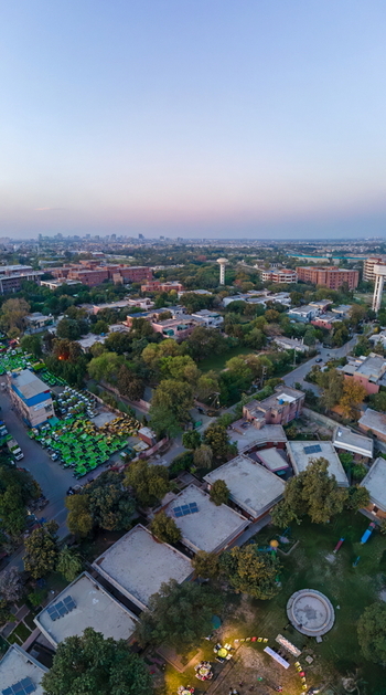Aerial view of the urban landscape featuring residential rooftops lush green trees and the distant Arfa Kareem Tower skyline during twilight in Lahore Punjab Pakistan. Aerial view of the urban landscape featuring residential rooftops lush green trees and the distant Arfa Kareem Tower skyline during twilight in Lahore Punjab Pakistan.