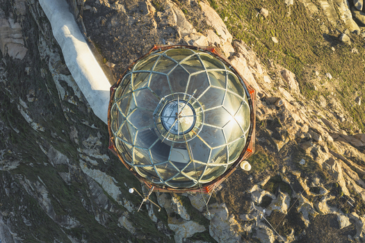 Aerial view of a lighthouse lantern room with a glass dome structure situated on a rugged rocky cliffside in Galicia Spain.