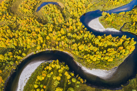 Aerial view of the Ljusnan river winding through a dense forest with vibrant autumn foliage in Bruksvallarna Jamtland County Sweden. Aerial view of the Ljusnan river winding through a dense forest with vibrant autumn foliage in Bruksvallarna Jamtland County Sweden.