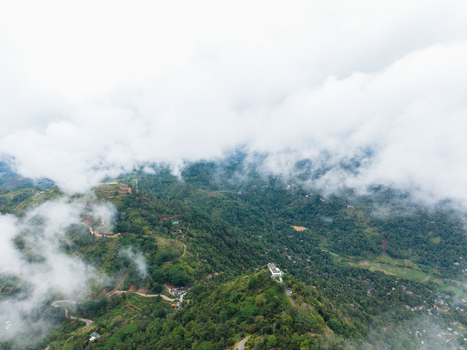 Aerial view of Ambuluwawa Tower surrounded by lush green hills and misty clouds over the valley Gampola Central Province Sri Lanka. Aerial view of Ambuluwawa Tower surrounded by lush green hills and misty clouds over the valley Gampola Central Province Sri Lanka.