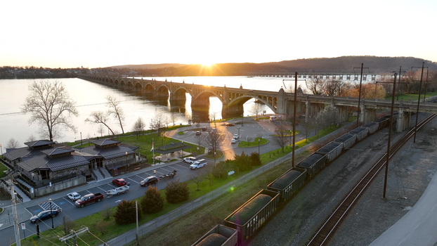 Aerial view of the Columbia Wrightsville Bridge spanning the Susquehanna River at sunset with a freight train on the tracks and a parking area in Columbia Pennsylvania United States. Aerial view of the Columbia Wrightsville Bridge spanning the Susquehanna River at sunset with a freight train on the tracks and a parking area in Columbia Pennsylvania United States.