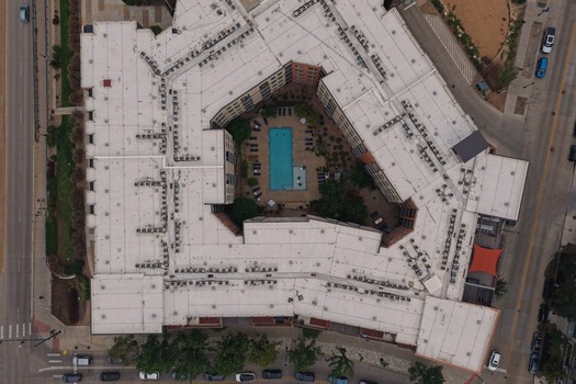 Aerial view of a modern apartment complex featuring a central courtyard with a swimming pool and surrounding lounge area in Denver Colorado United States. Aerial view of a modern apartment complex featuring a central courtyard with a swimming pool and surrounding lounge area in Denver Colorado United States.