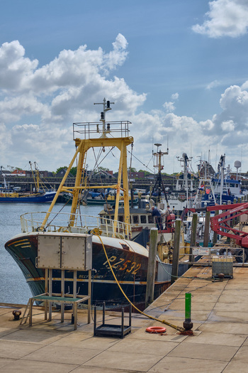 Den Oever Netherlands 18 May 2026 View of British fishing vessels being renovated at the Machinefabriek wharf with workers on deck under a cloudy sky.