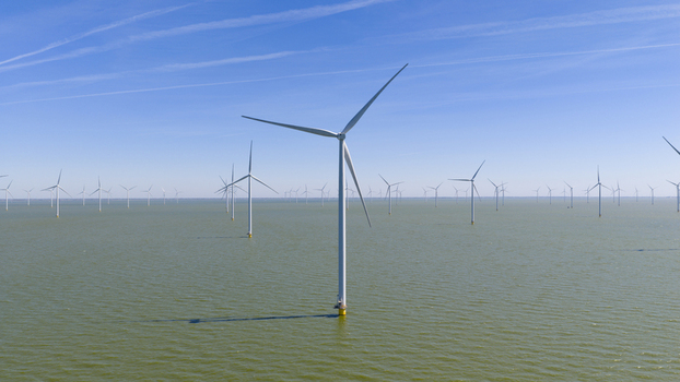 Aerial view of Windpark Fryslan offshore wind farm with numerous turbines rising from the calm waters of the IJsselmeer under a clear blue sky in Breezanddijk Friesland Netherlands. Aerial view of Windpark Fryslan offshore wind farm with numerous turbines rising from the calm waters of the IJsselmeer under a clear blue sky in Breezanddijk Friesland Netherlands.