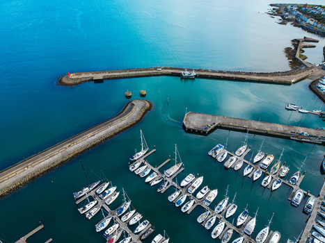 Aerial view of Bangor Harbour and Town featuring numerous sailboats moored in the marina stone breakwaters and calm blue waters in Bangor Northern Ireland United Kingdom.