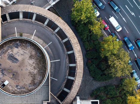 Aerial view of the circular concrete ramp of the ICC Berlin showcasing its distinctive brutalist architecture alongside a busy road with moving cars and surrounding greenery in Berlin Berlin Germany. Aerial view of the circular concrete ramp of the ICC Berlin showcasing its distinctive brutalist architecture alongside a busy road with moving cars and surrounding greenery in Berlin Berlin Germany.
