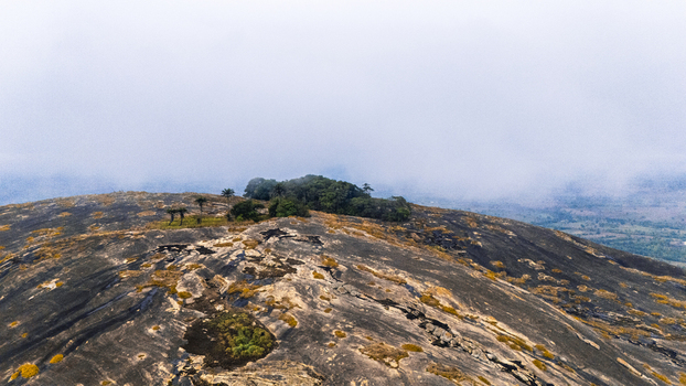 Aerial view of the rugged rocky landscape with patches of green vegetation contrasting against the dark stone under a cloudy sky Oyo Oyo Nigeria. Aerial view of the rugged rocky landscape with patches of green vegetation contrasting against the dark stone under a cloudy sky Oyo Oyo Nigeria.