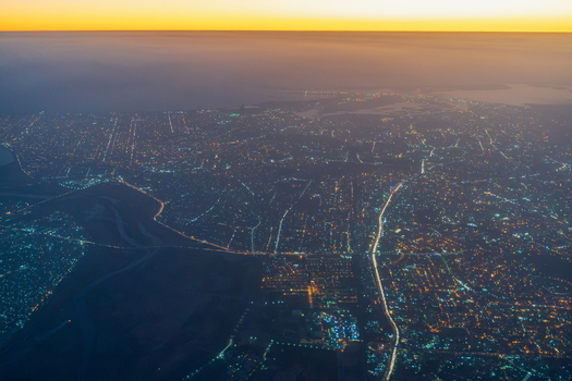 Aerial view of the sprawling city of Karachi at dusk with glowing street lights and illuminated roads stretching across the urban landscape in Karachi Sindh Pakistan.