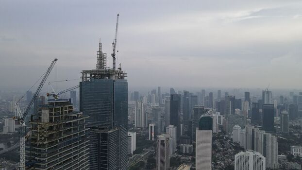 Kecamatan Menteng Indonesia 03 December 2021 Aerial view of skyscrapers under construction with tower cranes in Jakarta Pusat set against a cloudy sky over the urban sprawl. Kecamatan Menteng Indonesia 03 December 2021 Aerial view of skyscrapers under construction with tower cranes in Jakarta Pusat set against a cloudy sky over the urban sprawl.