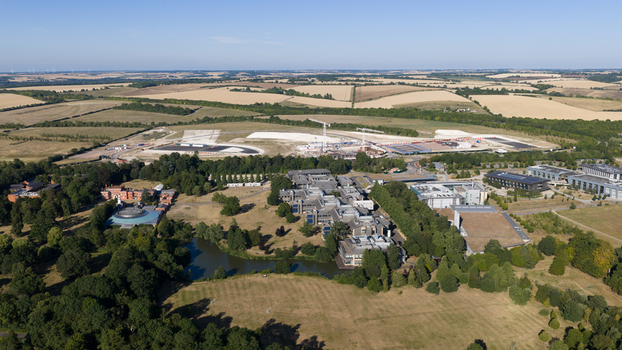 Aerial view of Wellcome Genome Campus featuring modern research buildings a small lake surrounding green spaces and construction areas in Hinxton England United Kingdom. Aerial view of Wellcome Genome Campus featuring modern research buildings a small lake surrounding green spaces and construction areas in Hinxton England United Kingdom.