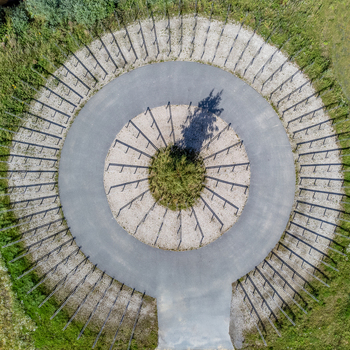 Aerial view of a circular structure with radiating lines a central green patch casting a dark shadow contrasted against surrounding grass Utopia Almere Netherlands. Aerial view of a circular structure with radiating lines a central green patch casting a dark shadow contrasted against surrounding grass Utopia Almere Netherlands.