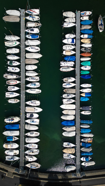 Aerial view of boats docked in the marina reflecting the turquoise water a vibrant juxtaposition against the gray docks Neuchâtel Neuchâtel Switzerland. Aerial view of boats docked in the marina reflecting the turquoise water a vibrant juxtaposition against the gray docks Neuchâtel Neuchâtel Switzerland.