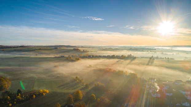 Aerial view of a rural landscape with morning fog sun rays and autumn fields in Germany. Aerial view of a rural landscape with morning fog sun rays and autumn fields in Germany.