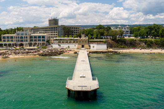 Aerial view of the pier at the Saints Constantine and Helena resort with a sandy beach clear sea and hotel buildings under a cloudy sky in Saints Constantine and Helena Varna Bulgaria.