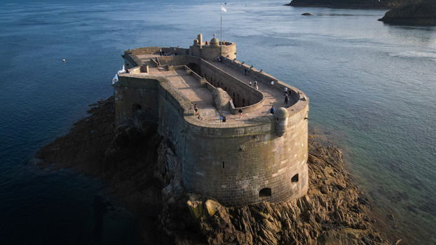Aerial view of the imposing Ch&acirc;teau du Taureau standing defiant against the crashing waves a historic fortress amidst the deep blue sea Plouezoc h Bretagne France.