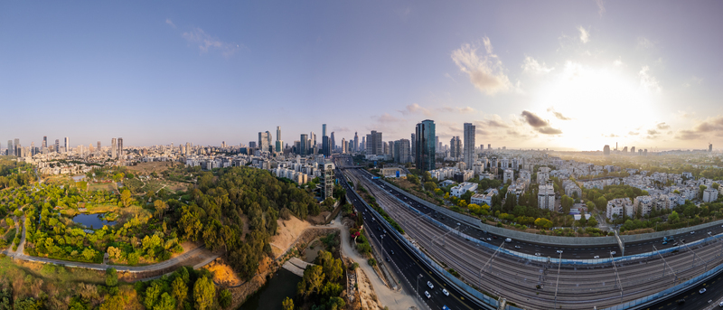 Aerial view of the Tel Aviv Yafo skyline at sunset featuring modern skyscrapers a green park and a busy highway with railway tracks in Tel Aviv Yafo Tel Aviv District Israel. Aerial view of the Tel Aviv Yafo skyline at sunset featuring modern skyscrapers a green park and a busy highway with railway tracks in Tel Aviv Yafo Tel Aviv District Israel.