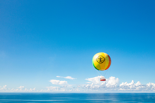 The Bahamas 12 October 2021 Aerial view of a tethered hot air balloon with the Royal Caribbean logo floating above the blue Caribbean Sea under a bright sky.