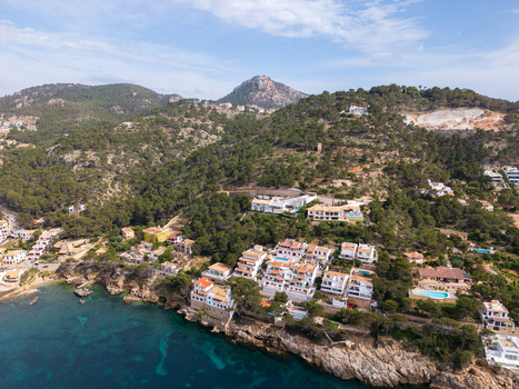 Aerial view of luxury white villas nestled on a lush green hillside overlooking the turquoise Mediterranean sea in Port d Andratx Balearic Islands Spain. Aerial view of luxury white villas nestled on a lush green hillside overlooking the turquoise Mediterranean sea in Port d Andratx Balearic Islands Spain.
