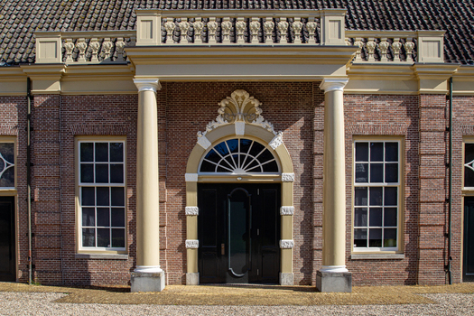 View of the grand entrance of Castle Groeneveld featuring a brick facade elegant columns and an arched doorway with ornate carvings in Baarn Utrecht Netherlands.