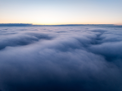 Aerial view of a thick sea of clouds under a soft sunrise sky Nuffield Oxfordshire United Kingdom. Aerial view of a thick sea of clouds under a soft sunrise sky Nuffield Oxfordshire United Kingdom.