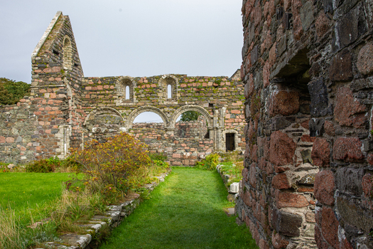 View of the Iona Nunnery ruins featuring ancient stone walls and arched windows set within a grassy courtyard Baile Mor Scotland United Kingdom. View of the Iona Nunnery ruins featuring ancient stone walls and arched windows set within a grassy courtyard Baile Mor Scotland United Kingdom.