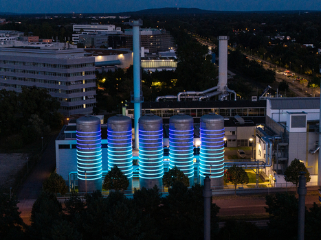 Aerial view of the BTB Heat and Power Plant Adlershof at night featuring glowing blue light rings on industrial tanks and surrounding buildings in Berlin Berlin Germany. Aerial view of the BTB Heat and Power Plant Adlershof at night featuring glowing blue light rings on industrial tanks and surrounding buildings in Berlin Berlin Germany.