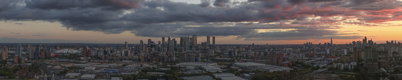 Aerial view of the London skyline at sunrise featuring Canary Wharf and The Shard under a dramatic cloudy sky in London Greater London United Kingdom.