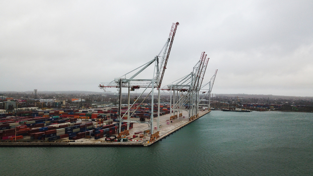 Aerial view of Southampton Port featuring large container cranes and rows of stacked shipping containers along the waterfront under a cloudy sky in Southampton United Kingdom. Aerial view of Southampton Port featuring large container cranes and rows of stacked shipping containers along the waterfront under a cloudy sky in Southampton United Kingdom.