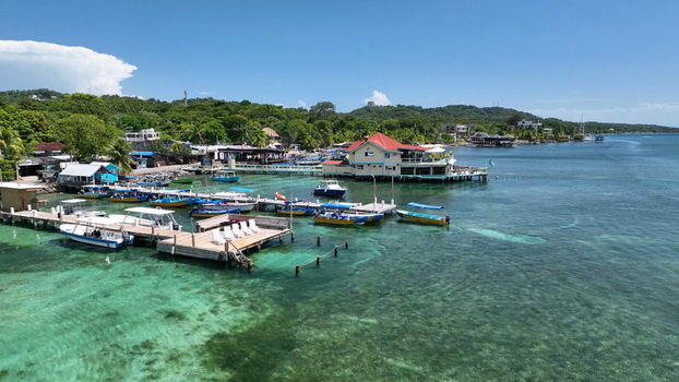 Aerial view of West End with its wooden piers colorful boats and clear turquoise water along the lush coastline of West End Bay Islands Department Honduras. Aerial view of West End with its wooden piers colorful boats and clear turquoise water along the lush coastline of West End Bay Islands Department Honduras.