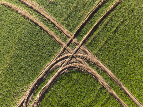 Aerial view of tractor tire tracks crossing through a lush green agricultural field under bright sunlight Meikleour Scotland United Kingdom. Aerial view of tractor tire tracks crossing through a lush green agricultural field under bright sunlight Meikleour Scotland United Kingdom.