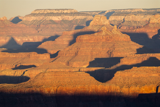 View of the Grand Canyon with rugged red rock formations and deep shadows cast by the golden hour light in Coconino County Arizona United States. View of the Grand Canyon with rugged red rock formations and deep shadows cast by the golden hour light in Coconino County Arizona United States.