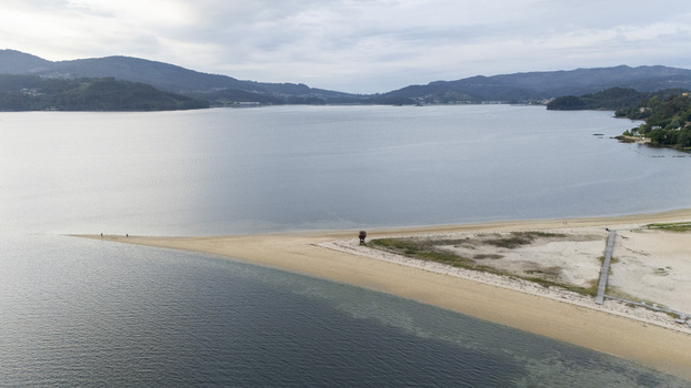 Aerial view of the Captain Nemo monument area on the sandy Cesantes beach spit surrounded by calm waters and green hills Vigo Pontevedra Spain.