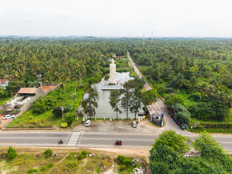 Aerial view of the Tsunami Honganji Viharaya standing Buddha statue surrounded by a pond and lush palm trees Peraliya Southern Province Sri Lanka. Aerial view of the Tsunami Honganji Viharaya standing Buddha statue surrounded by a pond and lush palm trees Peraliya Southern Province Sri Lanka.