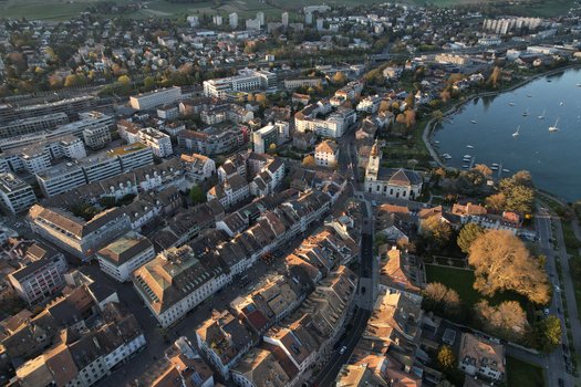 Aerial view of the historic town center with the Temple de Morges church traditional rooftops and boats moored on Lake Geneva during sunset in Morges Vaud Switzerland. Aerial view of the historic town center with the Temple de Morges church traditional rooftops and boats moored on Lake Geneva during sunset in Morges Vaud Switzerland.