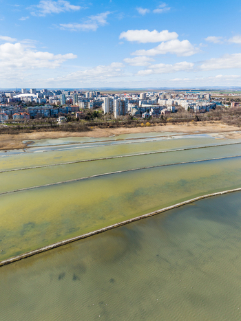 Aerial view of Lake Atanasovsko with salt pans and dividing walls near the city skyline under a blue sky in Burgas Burgas Bulgaria. Aerial view of Lake Atanasovsko with salt pans and dividing walls near the city skyline under a blue sky in Burgas Burgas Bulgaria.
