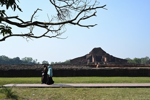 View of Sompur Mahavihara with two women walking on a path in the foreground under a clear sky in Naogaon District Rajshahi Division Bangladesh. View of Sompur Mahavihara with two women walking on a path in the foreground under a clear sky in Naogaon District Rajshahi Division Bangladesh.
