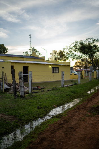 View of a yellow rural house with a wire fence and a small ditch in the foreground set against a sunset sky in Guaviravi Corrientes Province Argentina.