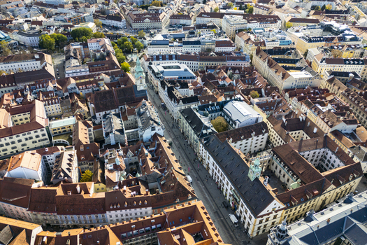 Aerial view of sunlight casting shadows across the red tiled roofs and cobblestone street main shopping street Herrengasse near the Hauptplatz the central square Graz Styria Austria.